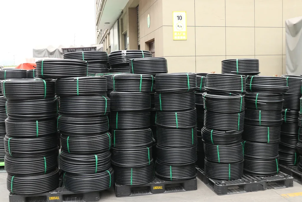 Bundled black HDPE pipe stacked in coils, the material family used for siphonic roof drainage because wall class can be specified for negative-pressure service