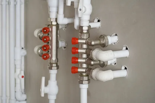 White PPR heating manifold with red-handled outlets, wall mounted